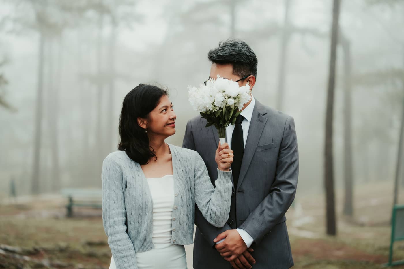 She looks up at him while a white bouquet hides his face