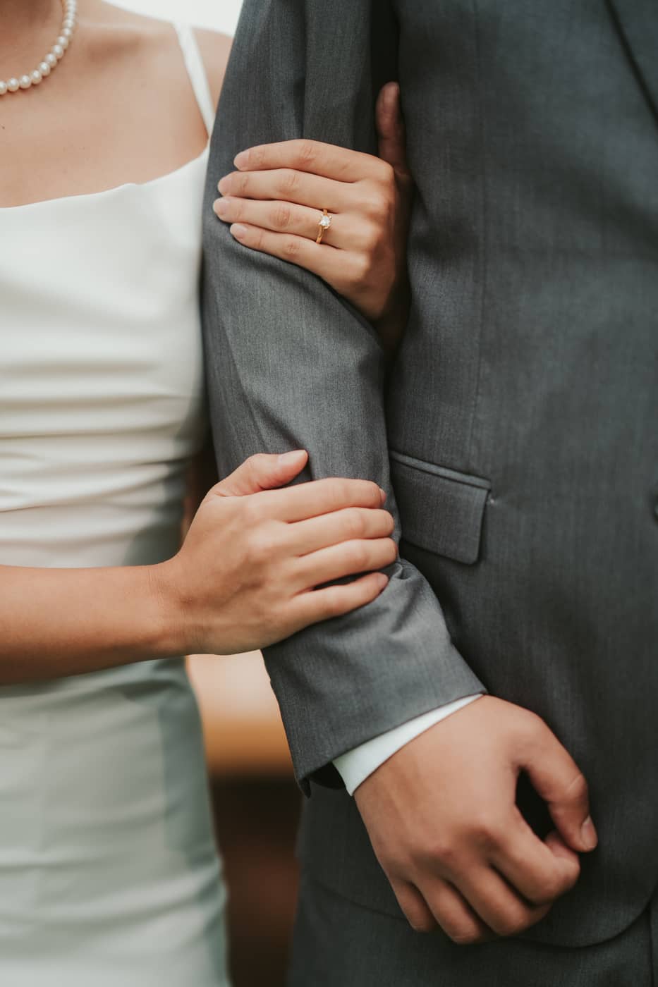 Her hands holding his arm, her engagement ring catching the light