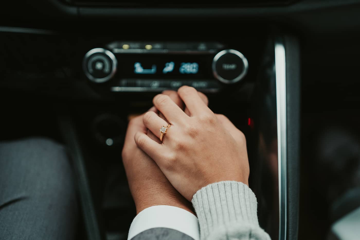Their hands clasped together, her engagement ring in focus